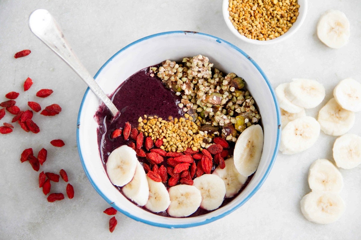 Blue and white enamel bowl filled with icy acai and topped with colorful superfoods.