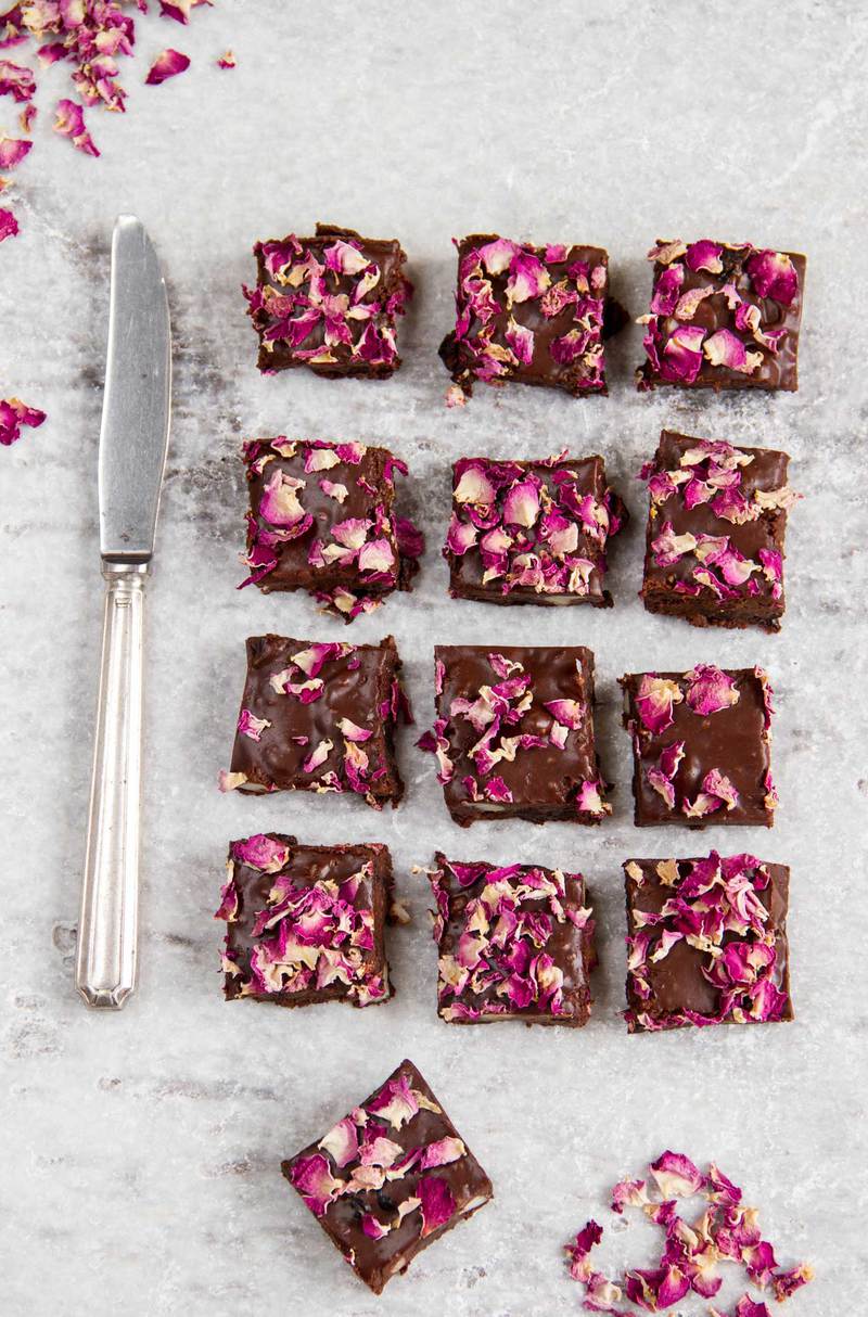 Overhead shot of freshly made and sliced squares scattered with pink rose petals, a vintage knife to the left.