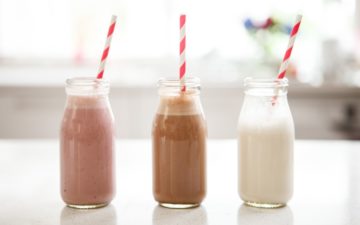 Three bottles of homemade cashew milk - all different flavours, sitting on the bench