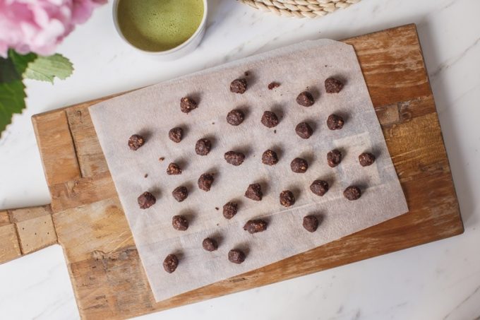 Raw cookie dough rolled into little balls, on a wooden board