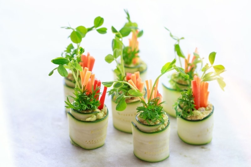 Zucchini roll-ups filled with fresh vegetables and microgreens, ready to serve at a party