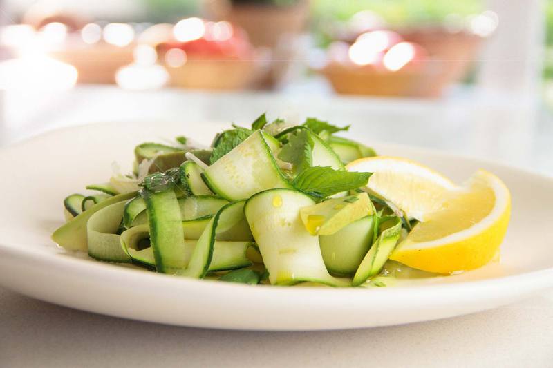 Close up of a plate of raw zucchini ribbons tossed in olive oil and lemon juice