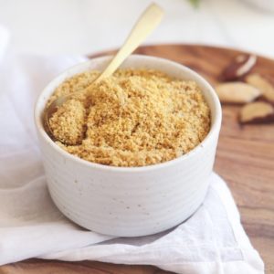 Ceramic bowl filled with a vegan parmesan, on a wooden platter