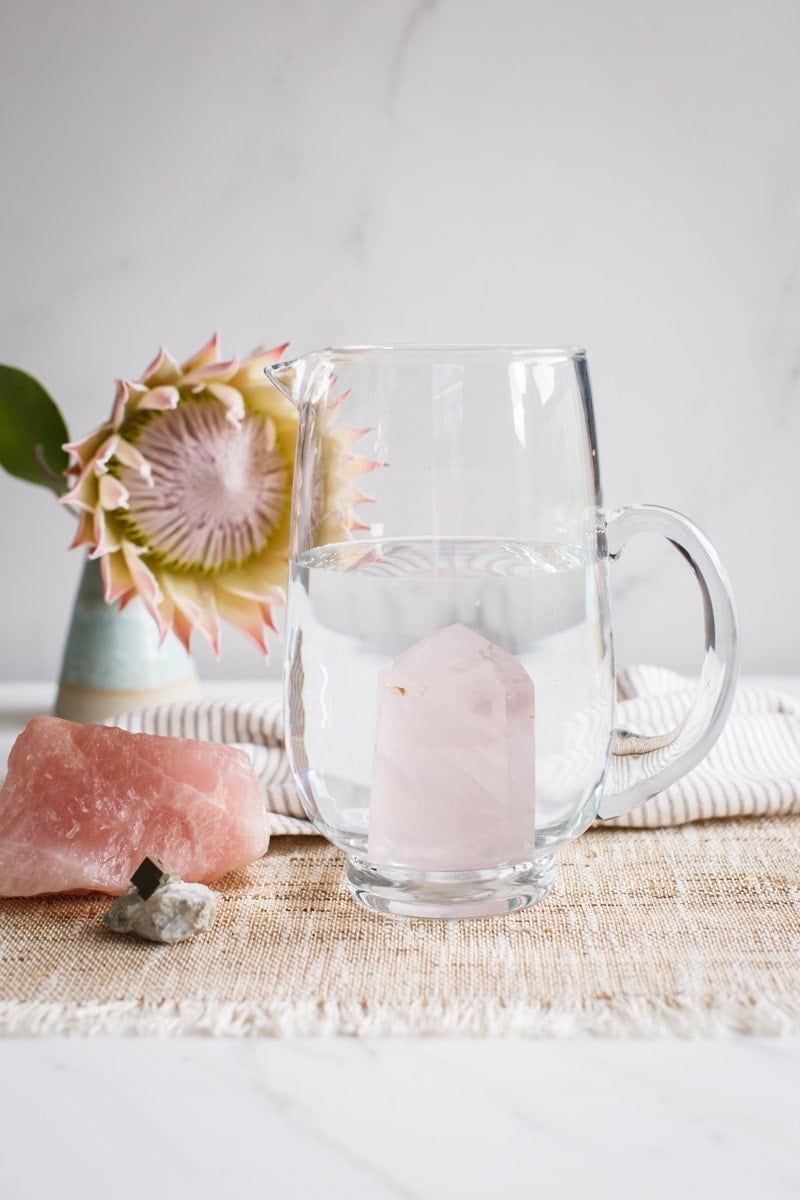 A large pitcher of water with a rose quartz inside, to infuse