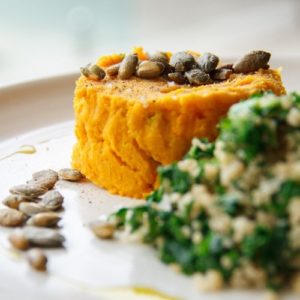 Pumpkin and bean mash plated next to quinoa and kale