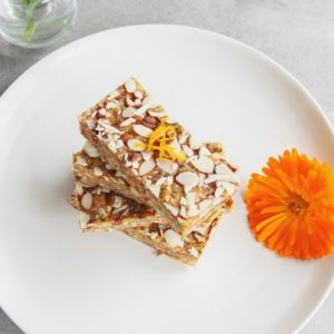 Raw bars stacked high on a plate with a calendula flower beside it as decoration