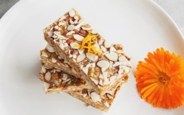 Raw bars stacked high on a plate with a calendula flower beside it as decoration