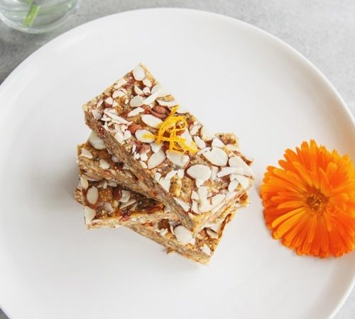 Raw bars stacked high on a plate with a calendula flower beside it as decoration