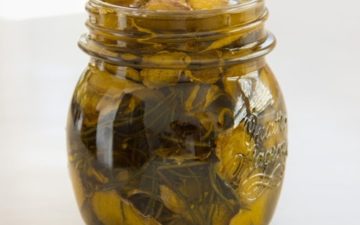 A herbal infused oil in a glass jar on the kitchen bench