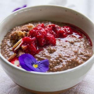 Close up of a bowl full of chocolatey chia pudding with raspberry jam on top