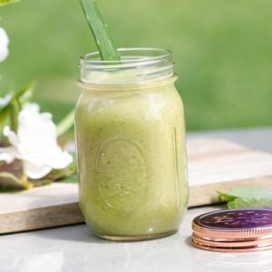 Green smoothie in a jar with a stick of aloe vera inside