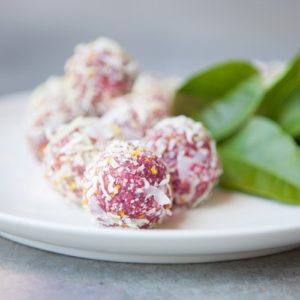Plate full of pink bliss balls rolled in desiccated coconut
