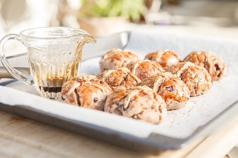 A tray of freshly baked gluten free hot cross buns sitting on an outdoor table