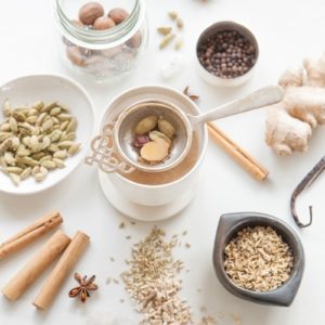 Cup of homemade masala chai surrounding by vanilla and spices