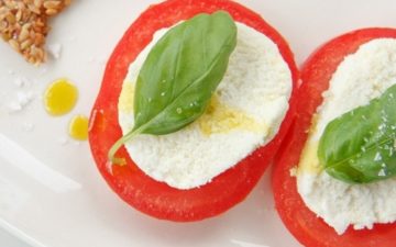 Close up of raw vegan mozzarella slices on thick sliced heirloom tomatoes topped with basil