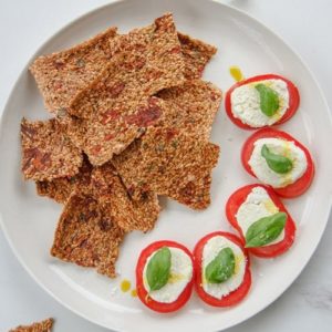 Close up of raw flax crackers arranged on plate with raw nut cheese beside it