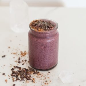 Bright purple smoothie in a glass jar on the kitchen bench