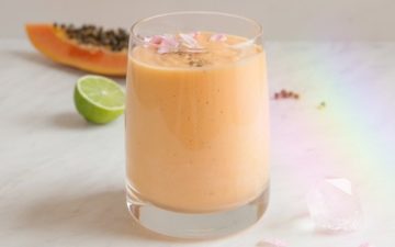 Glass of orange coloured papaya smoothie on the kitchen bench