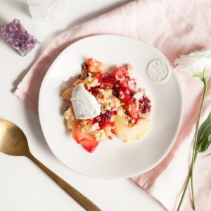 White plate on a pink linen napkin filled with hot apple crumble