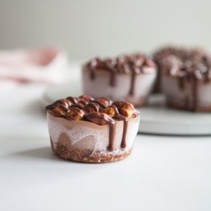 A mini chocolate raw vegan cheesecake drizzled with sauce sitting on the kitchen bench