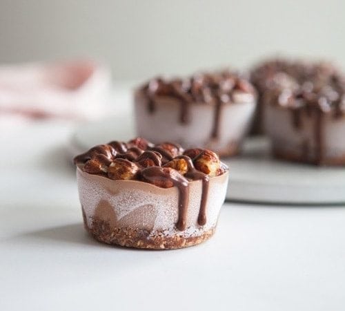 A mini chocolate raw vegan cheesecake drizzled with sauce sitting on the kitchen bench