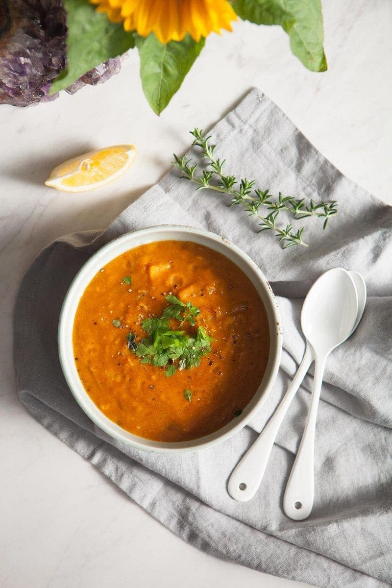 Nourishing Red Lentil Soup styled with flowers and fresh herbs