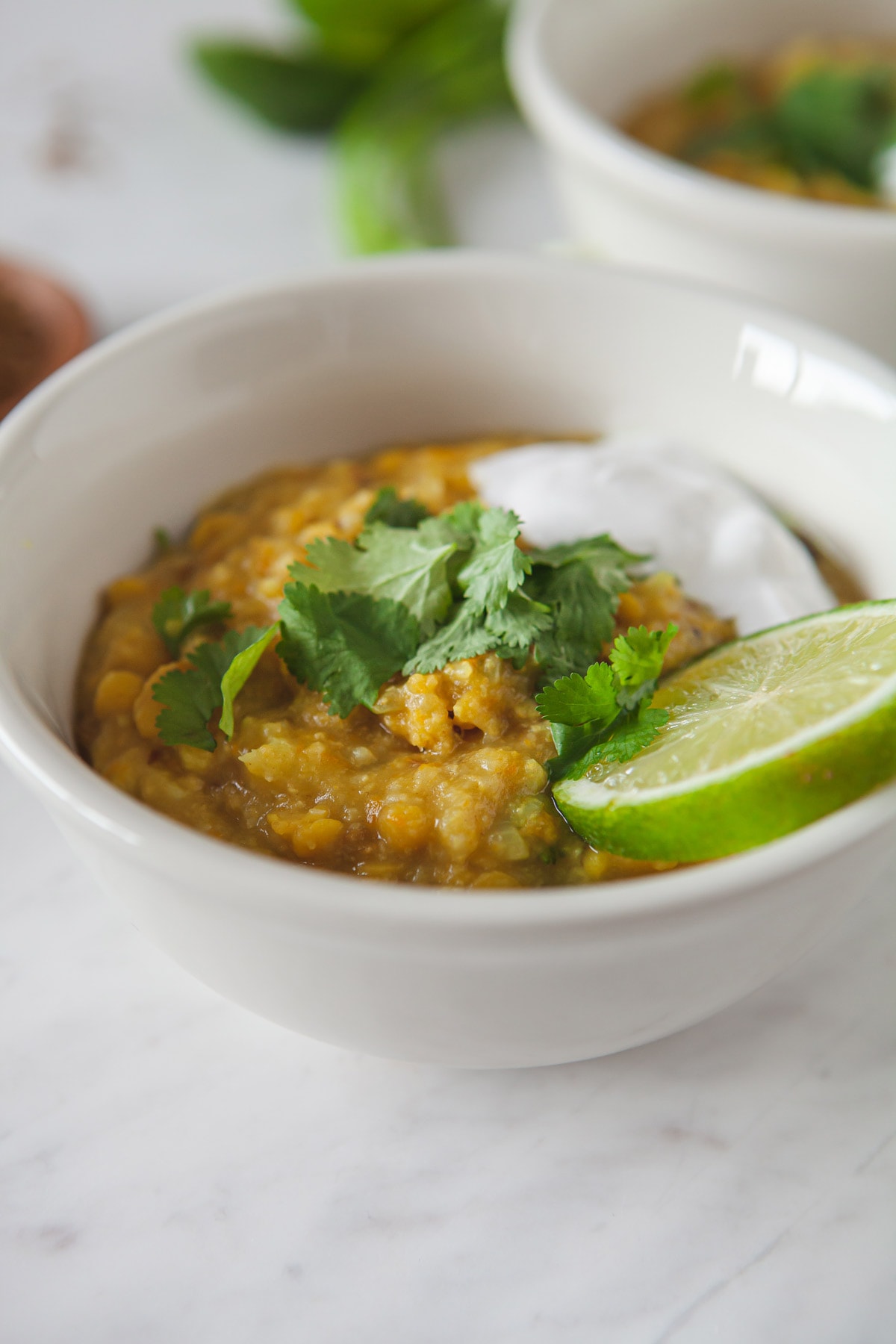 Close up of a bowl of this recipe, showing the consistency of the cooked mung beans and rice. Fresh coriander and lime are on top.