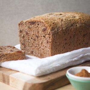 A loaf of homemade gluten free fruit spice bread on a bread board, sliced