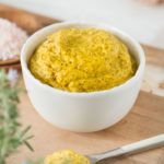 Close up of bright yellow mustard in a white dish