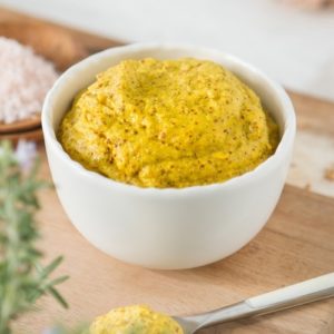 Close up of bright yellow mustard in a white dish