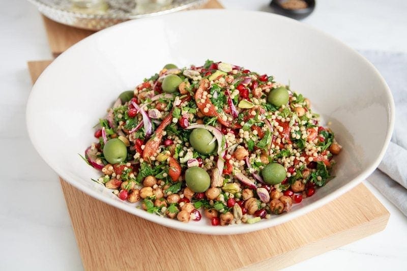 A colourful Sorghum Salad filled with green olives and pistachios, and red pomegranate, capsicum and onion