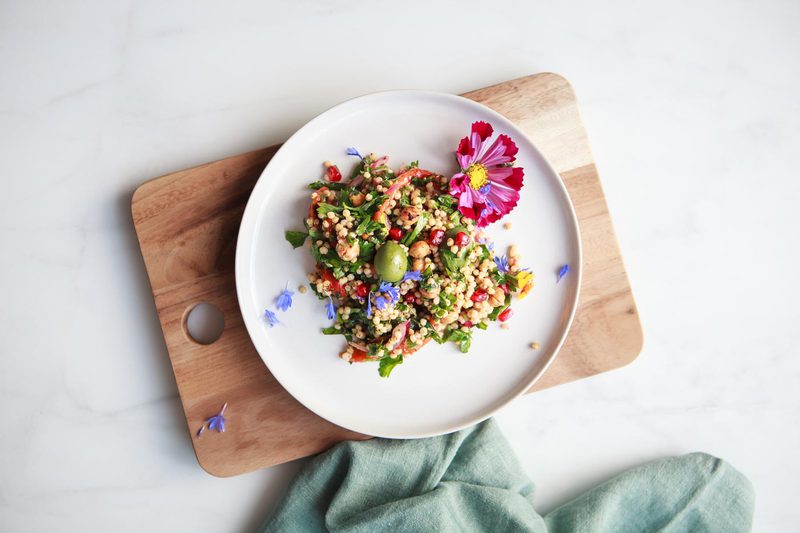 A single serving of colourful Moroccan sorghum salad on a plate with a pink flower 
