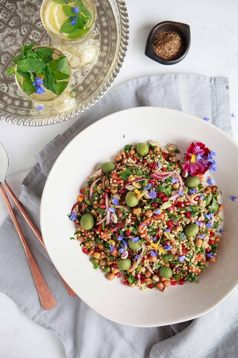 Chickpea Sorghum Salad in a large serving bowl with purple cornflowers scattered over the top