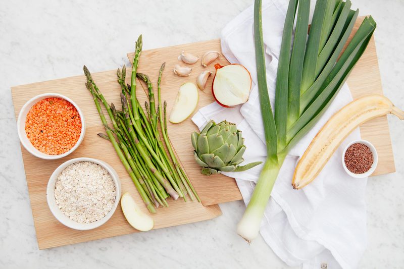 Wooden board filled with prebiotic rich fruits, vegetables, grains and lentils