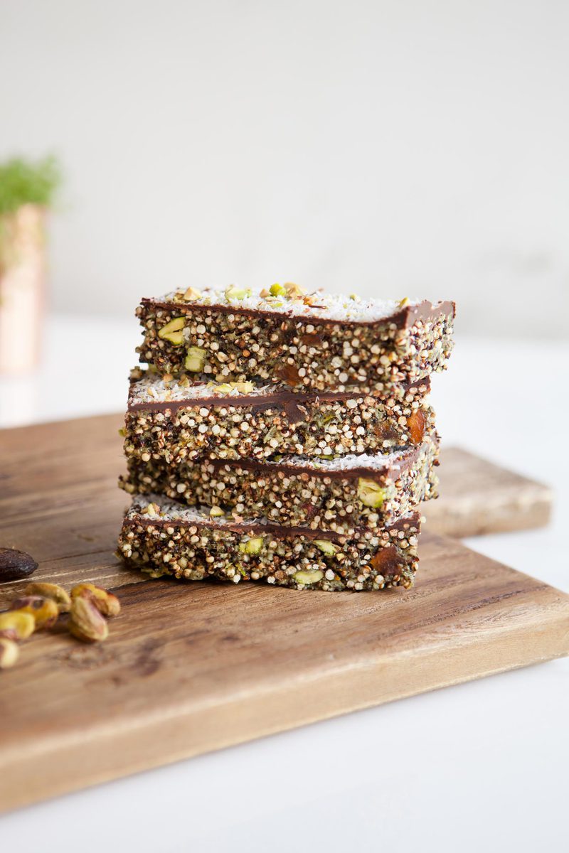 Stack of four popped quinoa bars with apricot and chocolate on a wooden board ready to enjoy