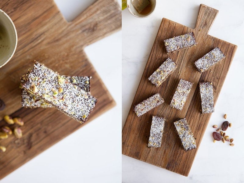 Overhead shot of popped quinoa bars coated in chocolate with desiccated coconut sprinkled over the top, on a wooden board