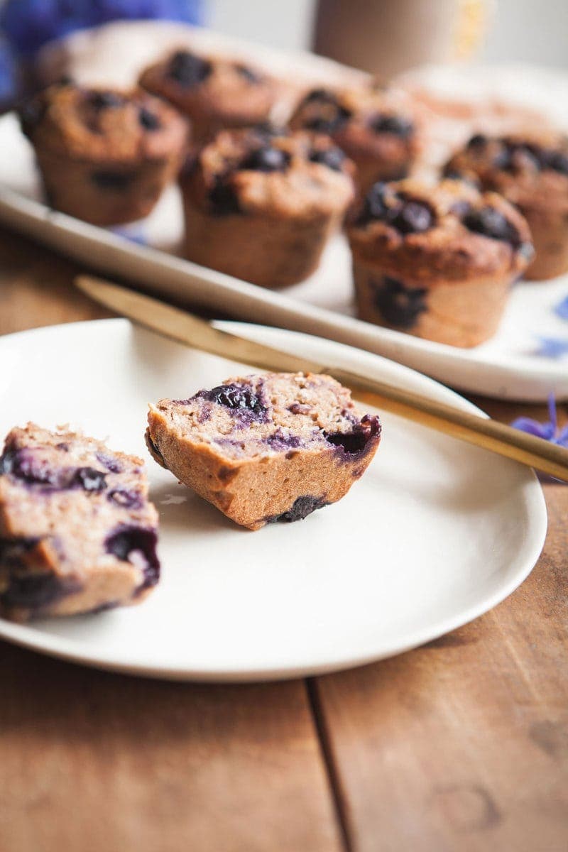 Gluten Free Blueberry Muffins cut in half on a ceramic plate, ready to spread with coconut butter