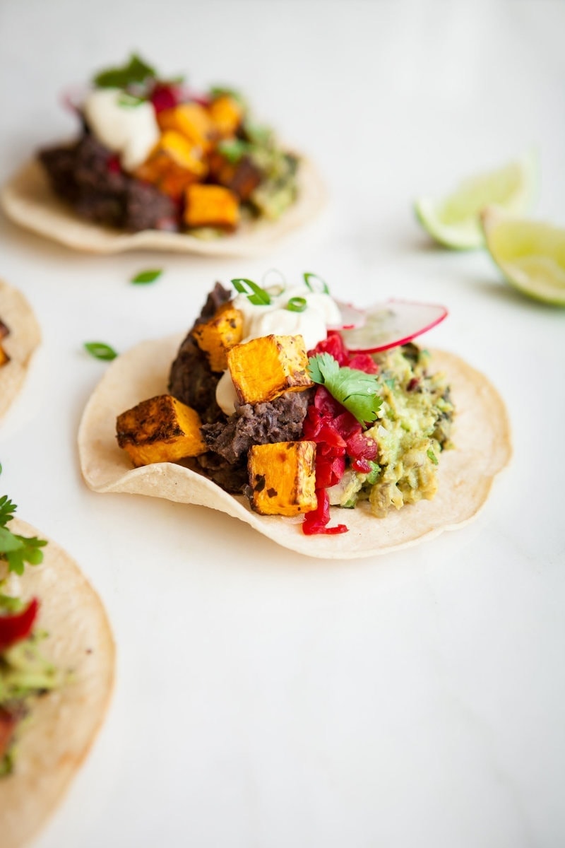 Healthy Butternut Squash Tacos with black beans on a white surface