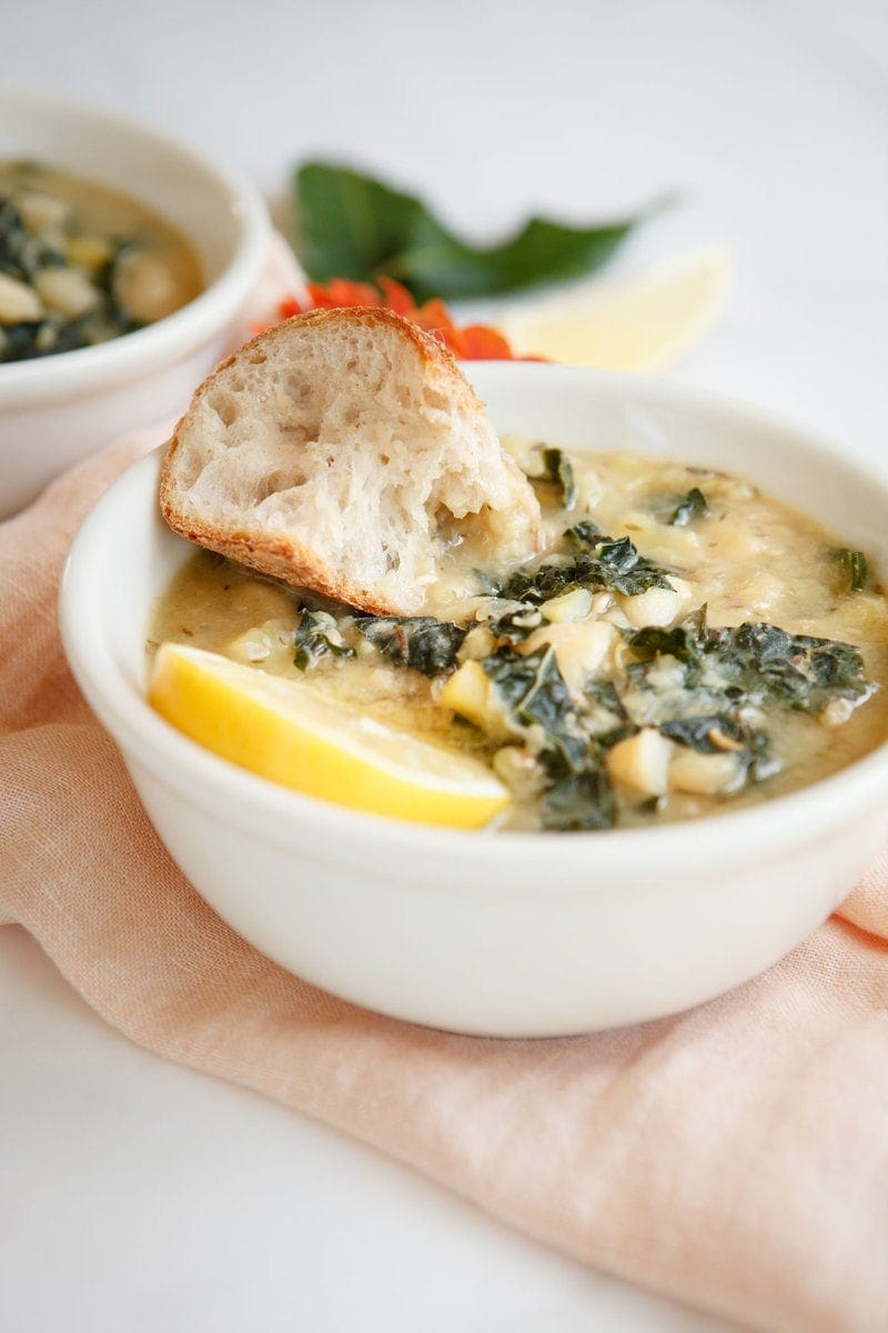 Side profile of the soup with a chunk of rustic bread dipped in, looks delicious!