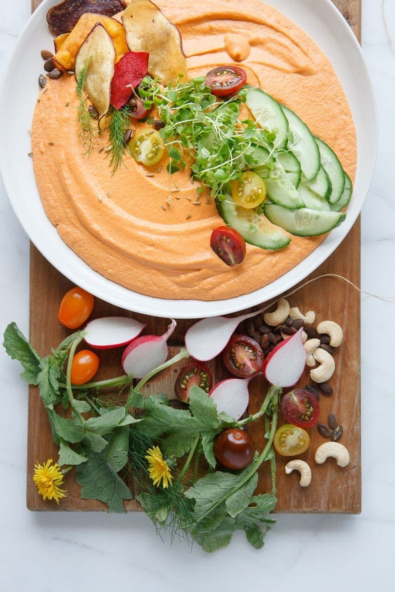 Chargrilled Capsicum Hummus close up with fresh micro greens and sliced cucumber on top