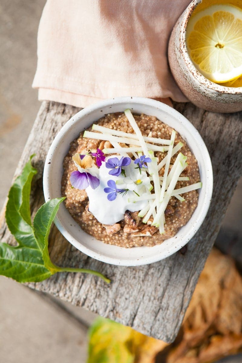 Close up of Quinoa Porridge with coconut, apple and fresh flowers on top