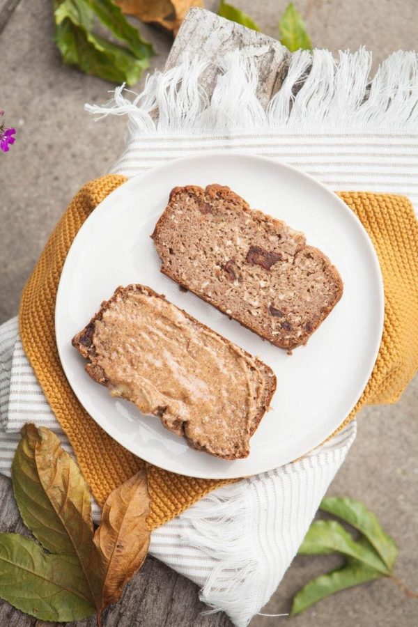 Two slices of freshly baked gluten free vegan banana bread, one spread thick with almond butter
