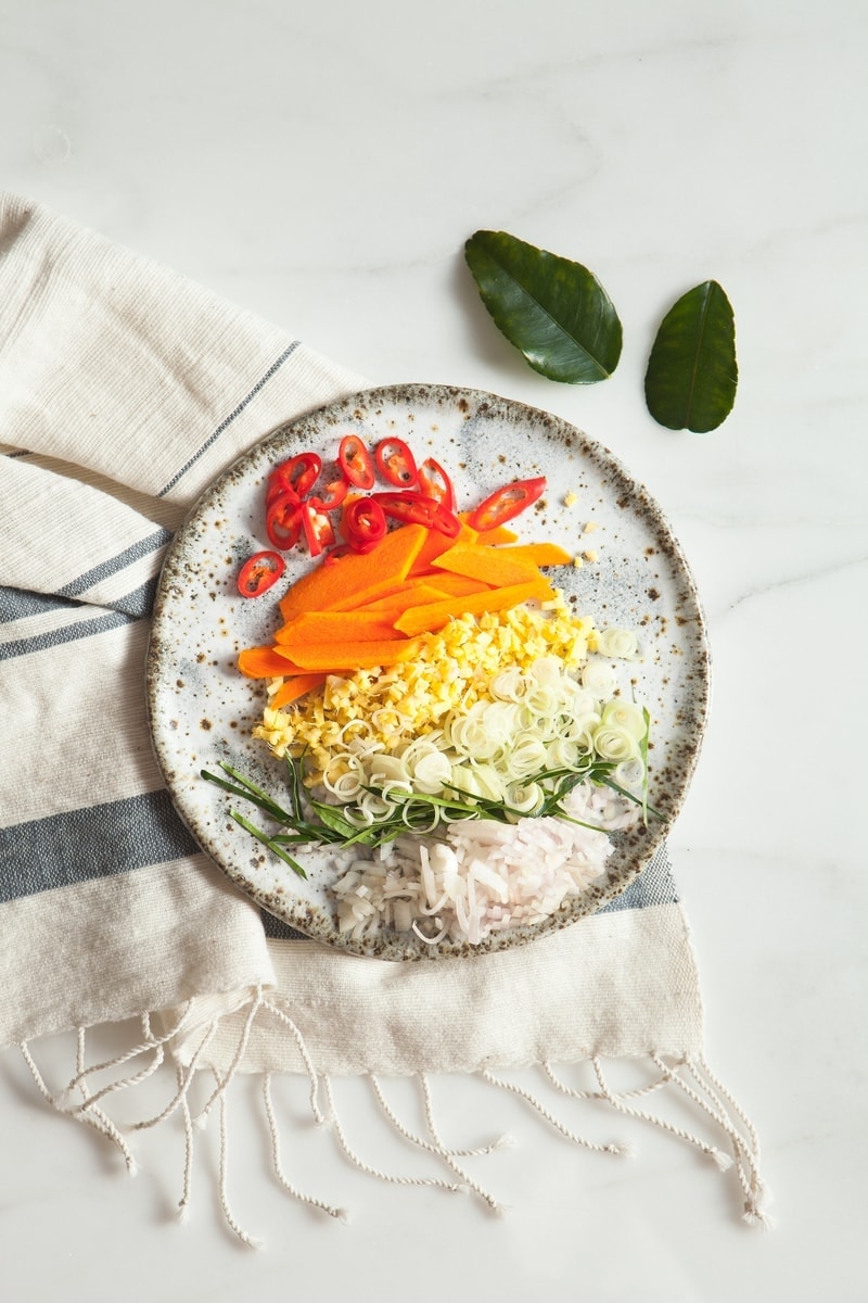 Speckled ceramic plate filled with a rainbow of aromatic spices used in anti-inflammatory soup - chilli, turmeric, ginger, lemongrass