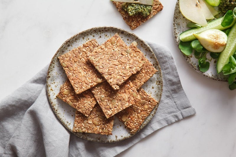 Speckled ceramic plate full of homemade seed crackers on a linen napkin