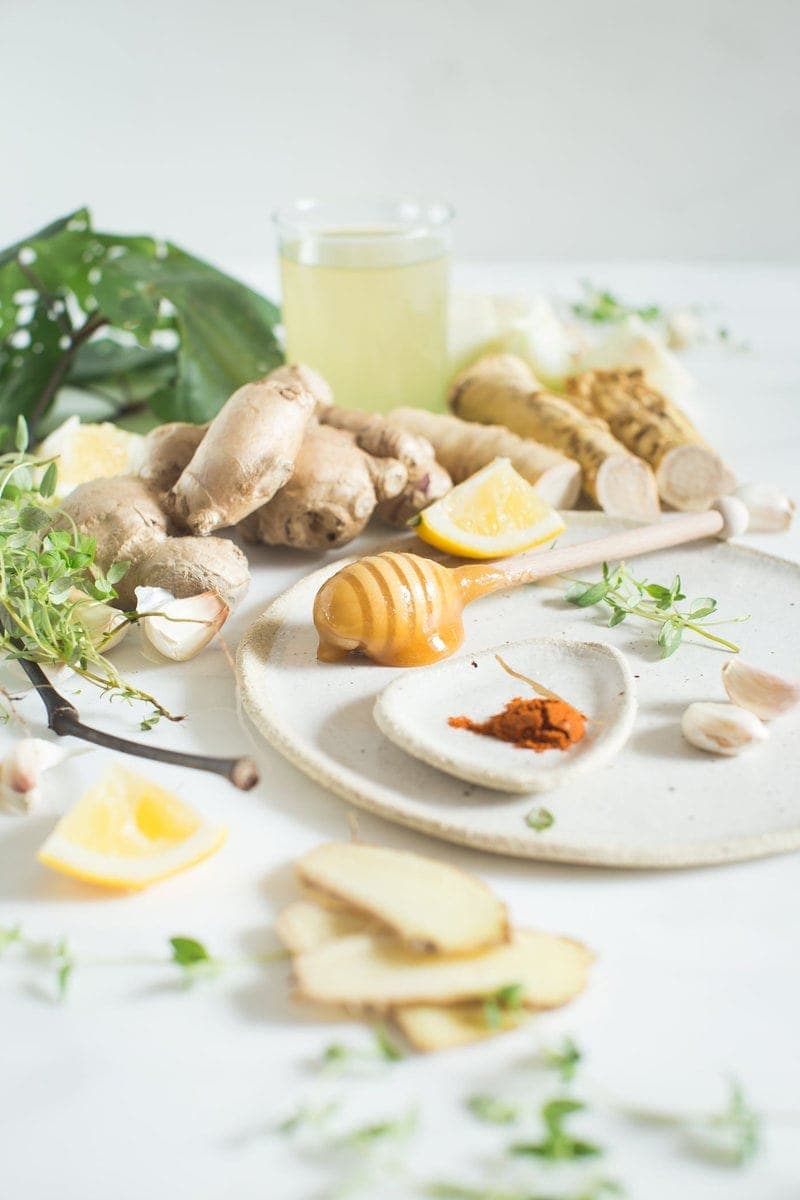 Medicinal Manuka honey on a honey dipper surrounded by other medicinal herbs and spices