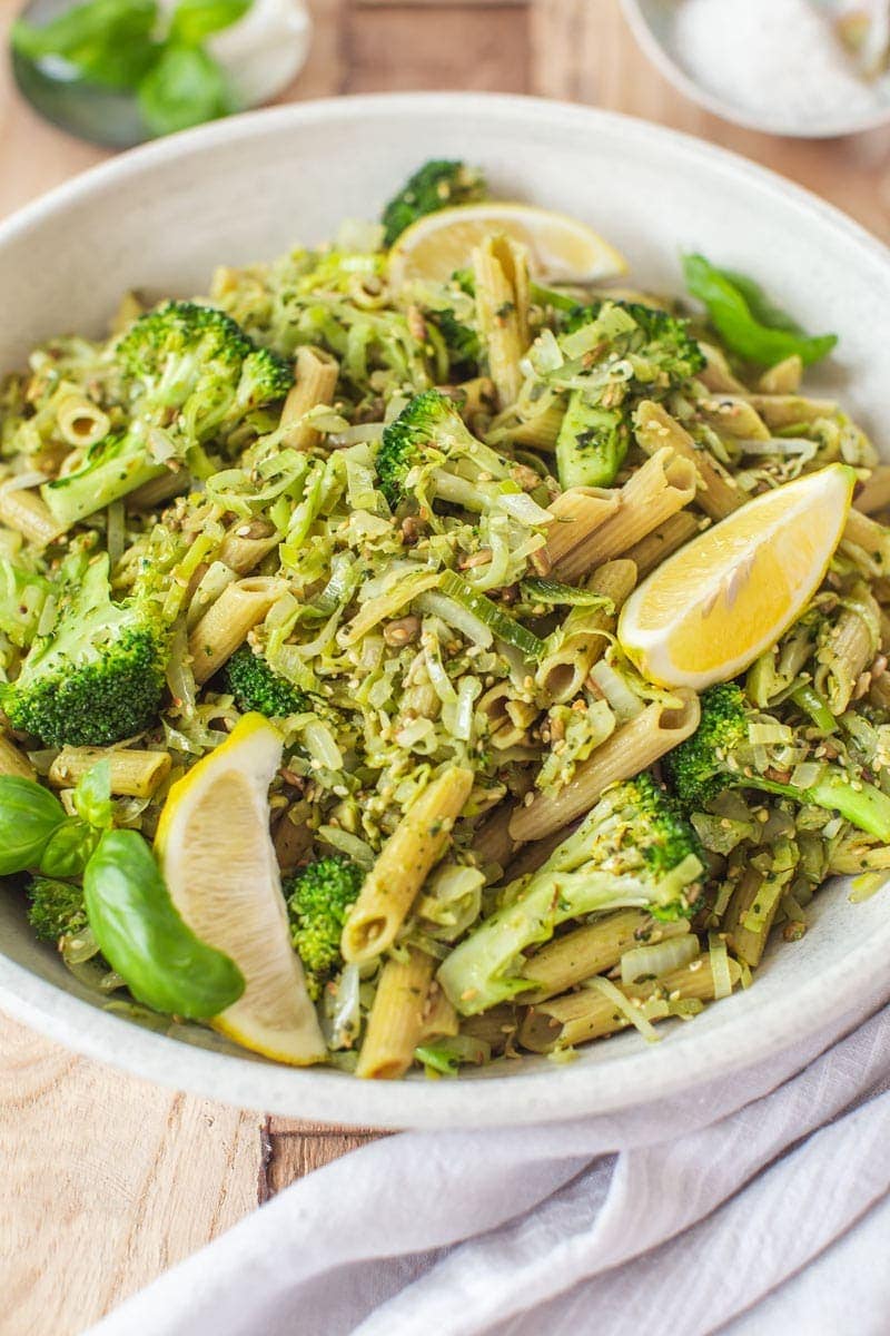 Serving bowl filled with broccoli pasta and fresh basil leaves