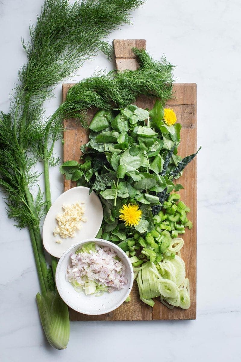Fresh ingredients for an easy watercress soup laid out on a wooden board