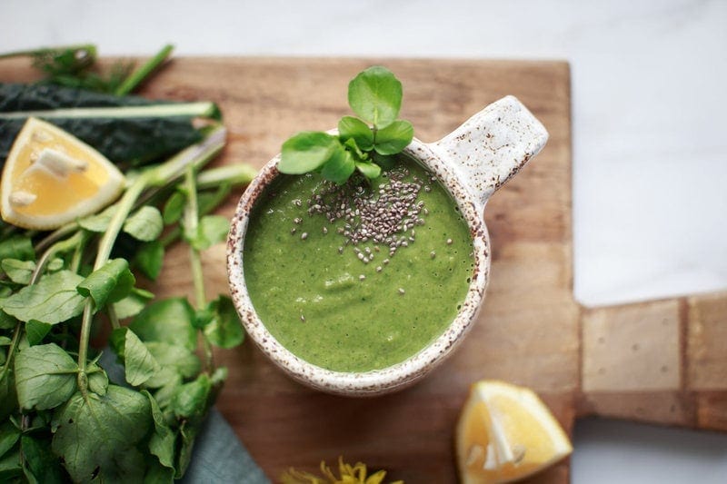 Bright green watercress soup in a rustic ceramic mug with a sprinkle of chia seeds on top