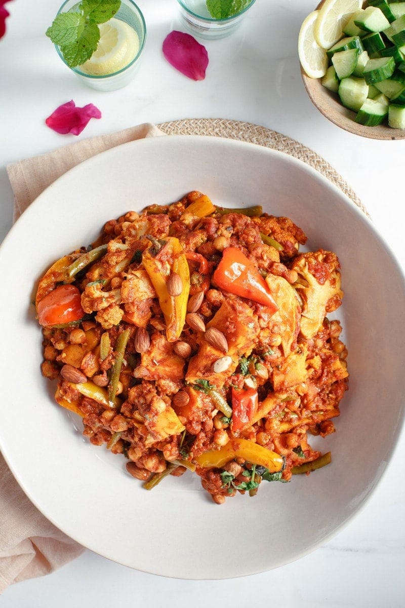 Close up of large ceramic bowl filled with Spiced Chickpea Vegetable Tagine and a small cucumber salad to the side