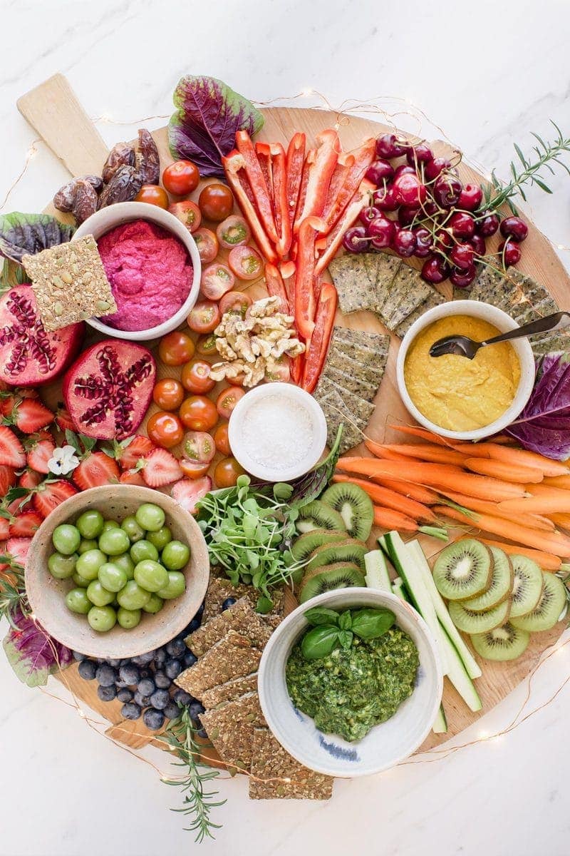 Vegan platter full of vibrant coloured dips, spreads, fruits, vegetables and crackers
